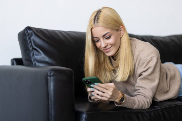 istock Smiling young lady chatting in social networks, watching funny videos, using mobile applications at home. 1399644344