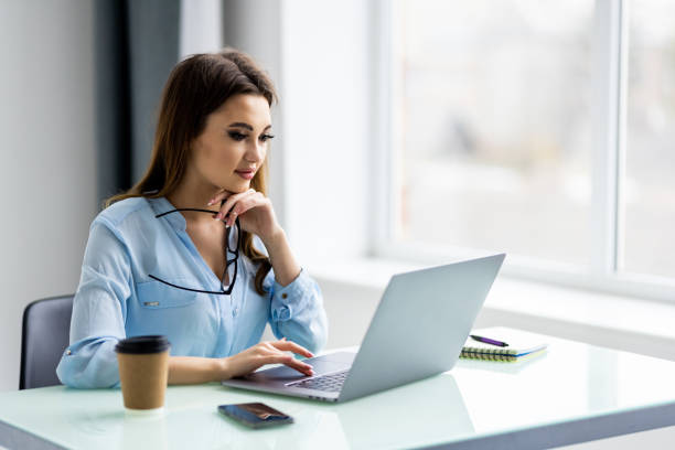 istock Young woman smiling while working with laptop in office 1399646351