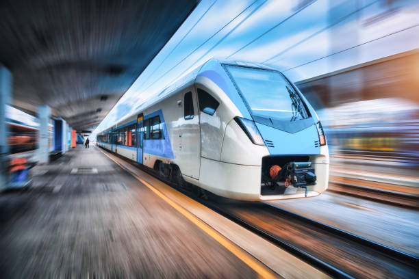 日没時に鉄道駅で動いている高速列車。鉄道のプラットフォームにモーションブラー効果を持つ青い近代的な都市間旅客列車。ヨーロッパの鉄道。商業輸送 - blurred motion city life train europe ストックフォトと画像