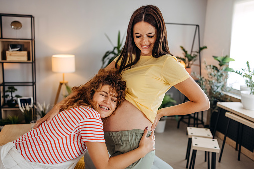 Female friend feeling belly of pregnant woman