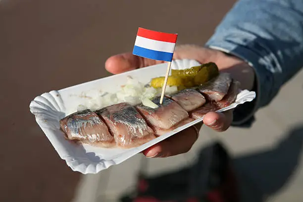 Ah, this is how we like it. Us, Dutchies. Well, only in Amsterdam, I might add. A herring cut into small pieces, tiny cuttings of onions and some gherkin. Everybody else in Holland just stuck it into their troat. The whole fish! Okay, without the head...
