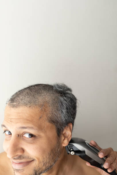 istock Handsome gray-haired man is cutting hair himself. 1399657721