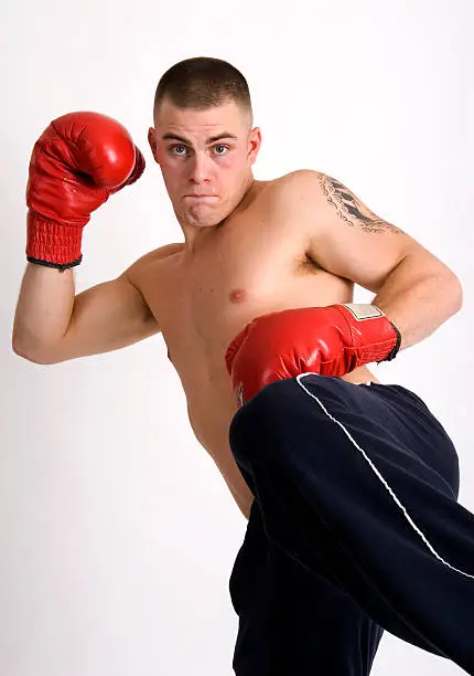 Angry looking young man practicing kick boxing moves