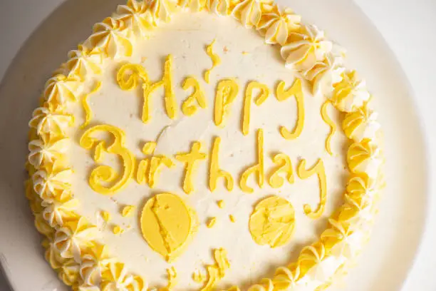 Lemon flavoured Happy Birthday Sponge cake with yellow decorative icing.
