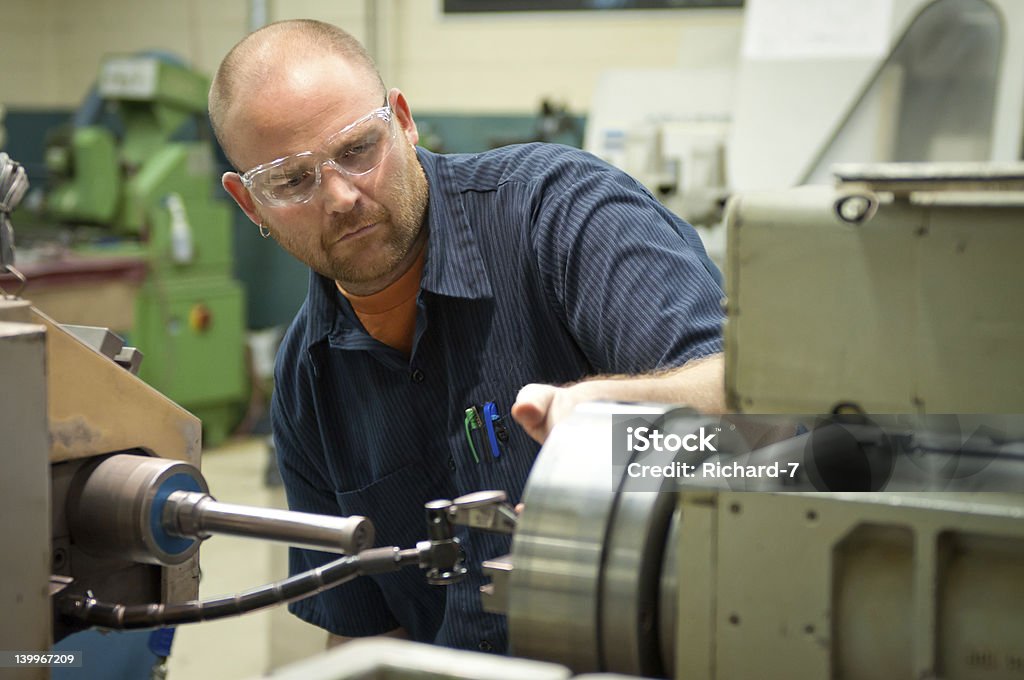 Professional Machinist with Saftey Glasses Professional Trade - Adult Male with safety glasses working a Precision Cylindrical Grinder grinding parts for the power gen. industry. 30-39 Years Stock Photo