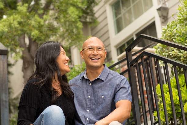 Happy Asian couple smiling and hugging outside.