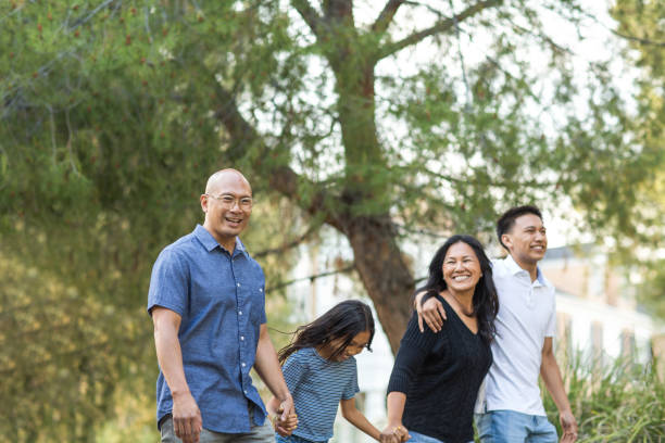 Happy Asian family walking and talking outside. Asian family taking a walk outside and talking. filipino family stock pictures, royalty-free photos & images