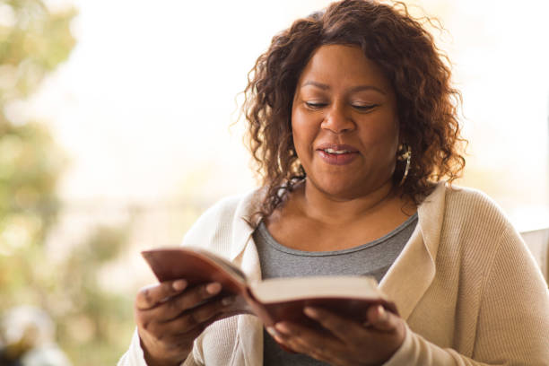 madura mujer afroamericana sentada afuera leyendo. - reading religious text black bible fotografías e imágenes de stock
