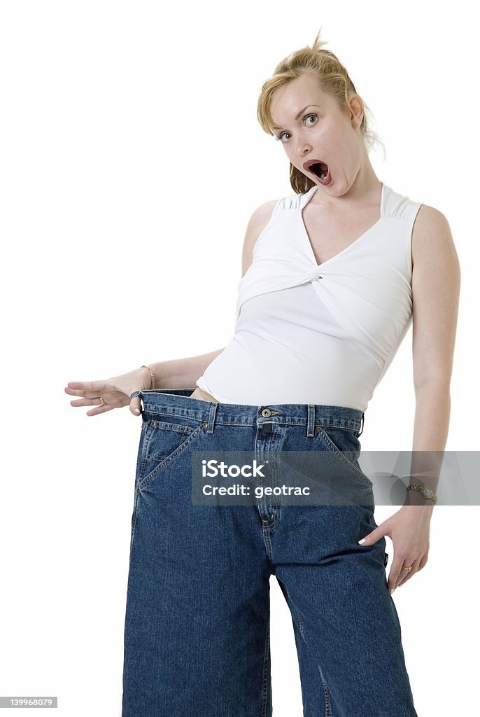 Can you believe this? Woman demonstrating weight loss by wearing an old pair of jeans four sizes too big and pointing to her stomach Abdomen Stock Photo