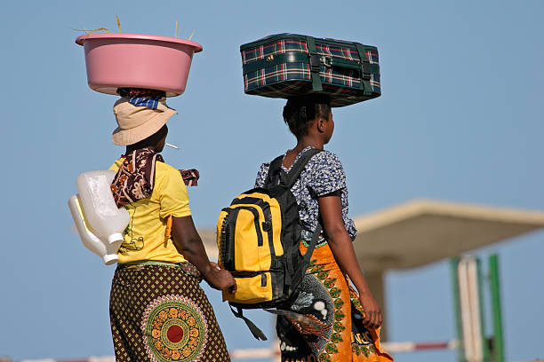 Mozambican woman in traditional dresses carrying their luggage on their heads
