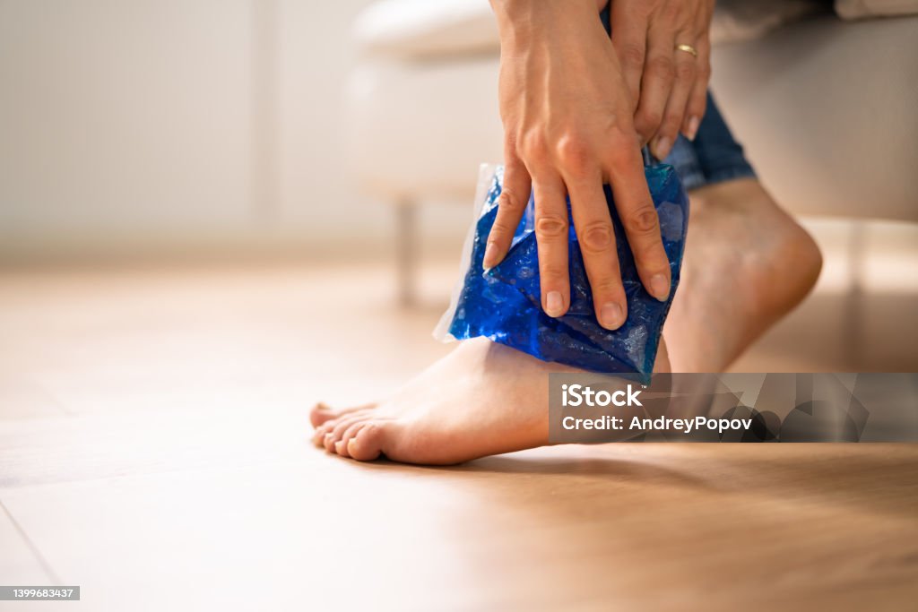 Woman Applying Ice Gel Pack On Her Ankle Close-up Of A Woman's Hand Applying Ice Gel Pack On Her Ankle Ice Pack Stock Photo