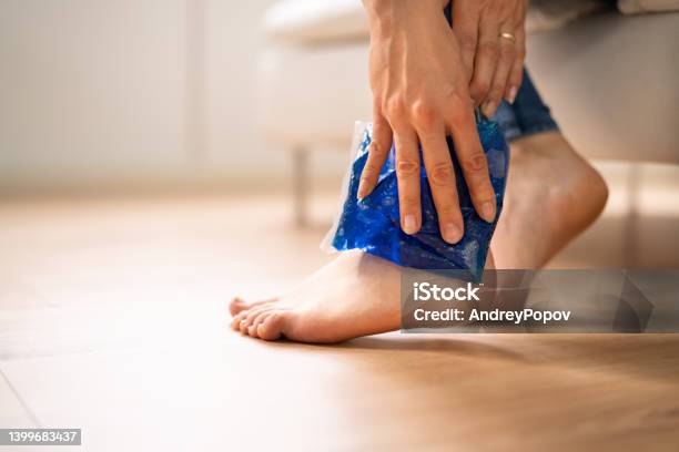 Woman Applying Ice Gel Pack On Her Ankle Stock Photo - Download Image Now - Ice Pack, Icing, Ankle