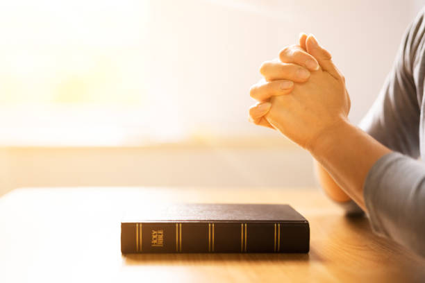 istock Woman's Hand Over Holy Bible Book 1399683444