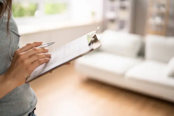 Close-up Of A Woman's Hand Filling Real Estate Appraisal Form With Pen