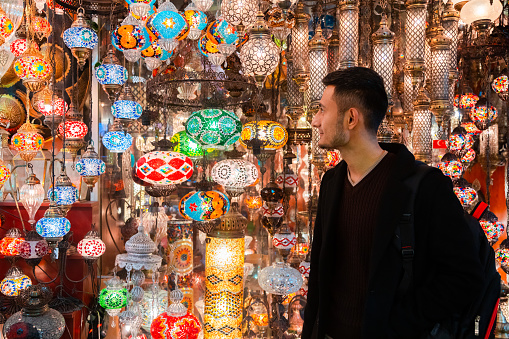 Young man looking at Turkish lamps for sale in the Grand Bazaar, Istanbul, Turkey