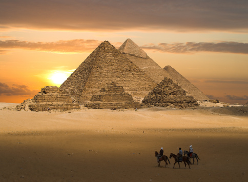 Pyramids of Gizeh near Cairo in Egypt. In this artistic photo the sky was replaced by a sunset.