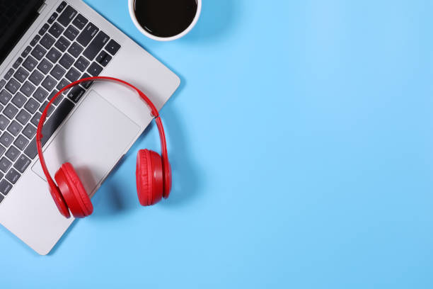 istock Red headphone placed on laptop with black coffee cup isolated on light blue background. Flat lay photography with copy space. 1399689201