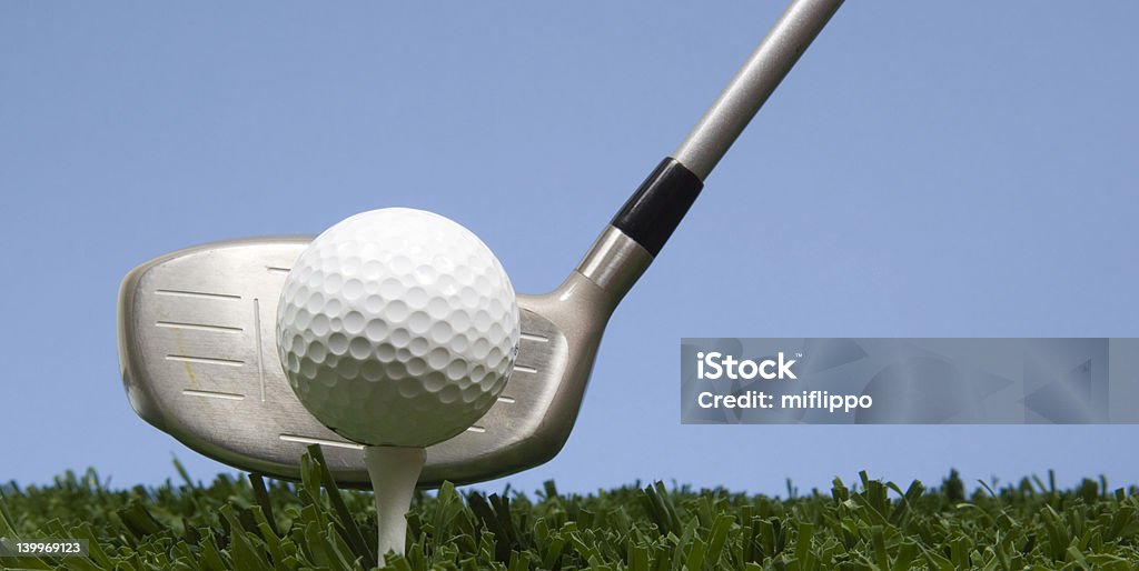 Golf ball and tee on grass with driver golf ball on tee on grass with blue sky with a driver Blue Stock Photo