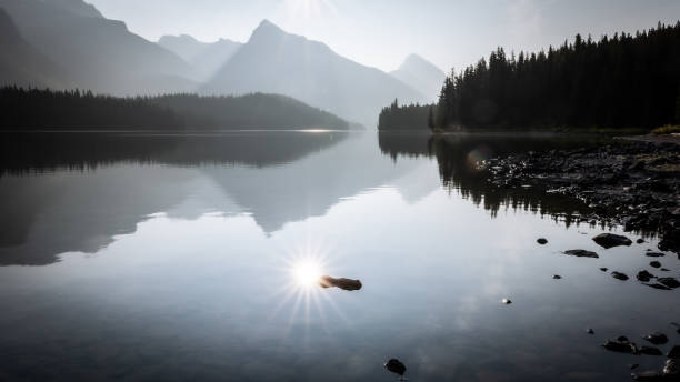 istock Sun reflecting in still alpine lake surrounded by mountains and forest, Jasper NP, Canada 1399691581