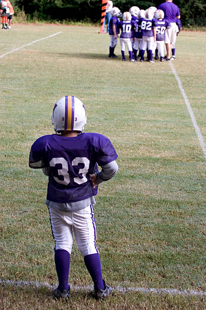 peewee jugador de fútbol viendo equipo de banda - youth league american football childhood helmet fotografías e imágenes de stock