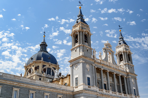 Side view of the Cathedral of Saint Mary the Royal of La Almudena on the blue sky background with white clouds in summer time in Madrid, Spain. Madrid is a popular tourist destination of Europe.