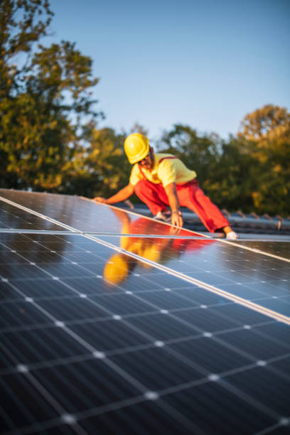 Technician fitting solar panels to a house roof. stock photo