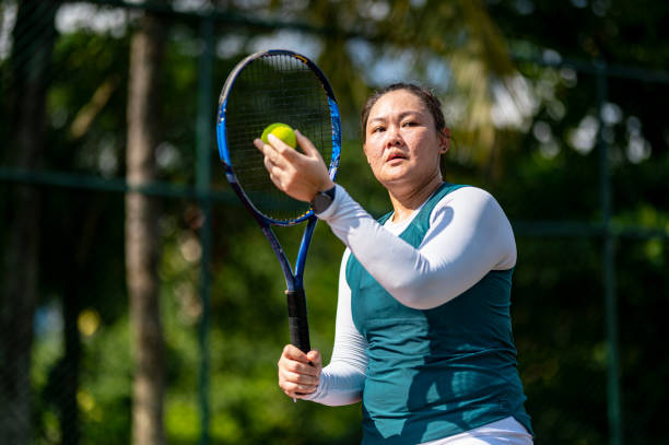 asiatische chinesin, die am wochenendmorgen auf dem tennisplatz übt - tennis serving female playing stock-fotos und bilder