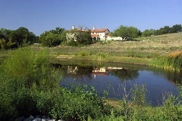 Hacienda style home overlooking small pond.