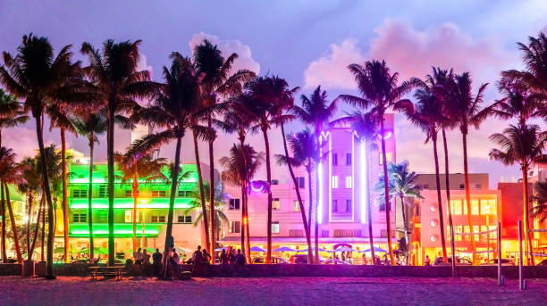 hoteles y restaurantes de miami beach ocean drive al atardecer. horizonte de la ciudad con palmeras por la noche. vida nocturna art decó en south beach - vida nocturna fotografías e imágenes de stock