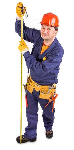 istock A worker in a helmet measures with a tape measure. 1399700363