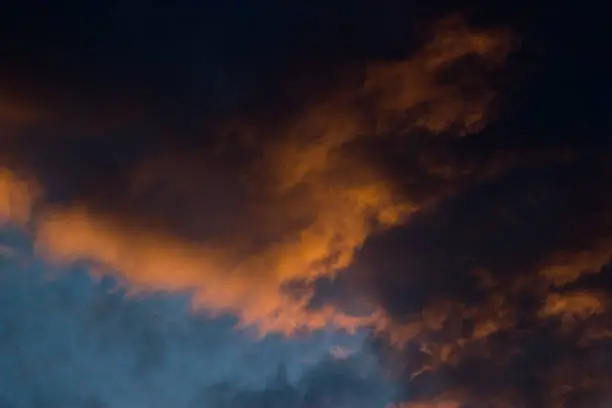 Strong contrast between the fringes of the clouds lit by the setting sun