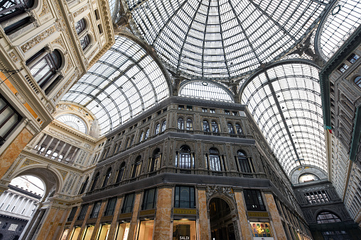 Galleria Umberto I in Naples City. The image shows the famous covered shopping mall in Naples with several pedestrians. The building was opened in 1890 and planned by Emanuele Rocco, captured during summer season.