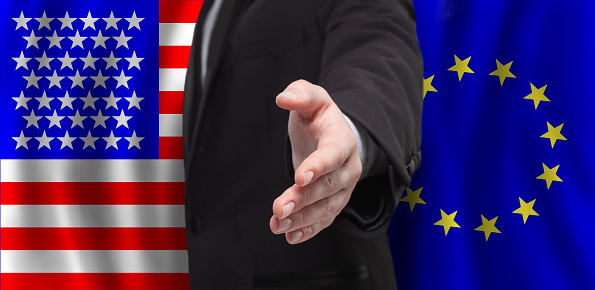 USA and European Union flags with open male hand for handshake