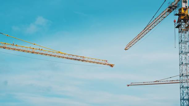 istock Jib Arms of Tall Construction Site Industrial Cranes Lifting Cargo 1399705782
