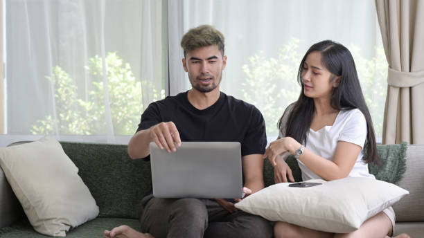 istock Loving young couple relaxing on sofa and surfing internet with computer laptop together. 1399705896