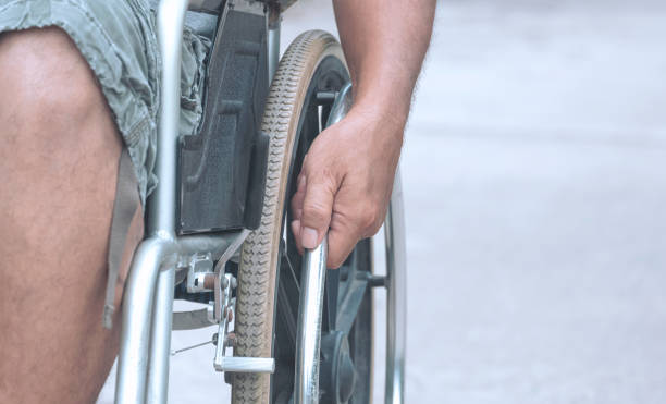 istock Focus at disabled man's hand manually pushing wheelchair on pavement in public park 1399709129