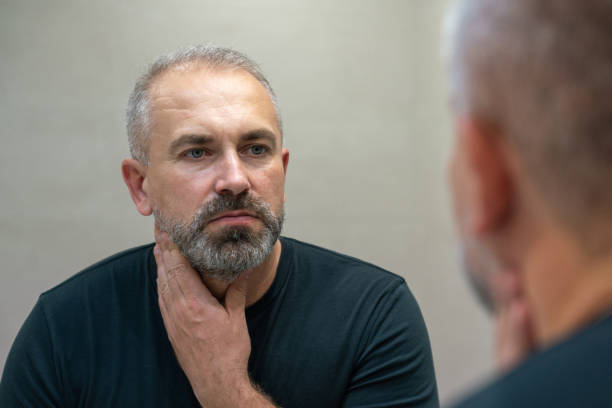 istock Middle-aged handsome man looking in mirror in bathroom touching his beard thinking of cutting it off 1399712173