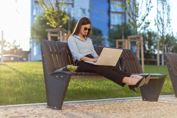 istock Business woman is sitting on bench outdoors and using lap top for working out office 1399714031