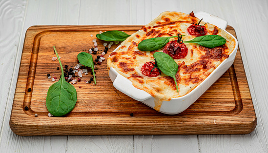 Baking dish with tasty vegetable lasagna on wooden background. Healthy food. Photo for the menu.