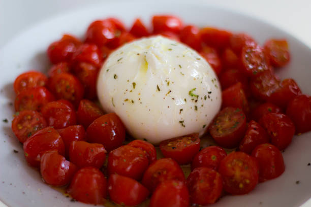pomodorini con una burrata al centro e spezie. - mozzarella tomato antipasto appetizer foto e immagini stock