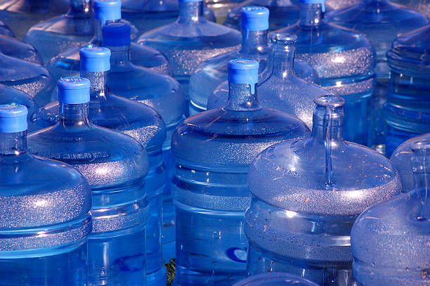 Many large blue water jugs some with caps stock photo