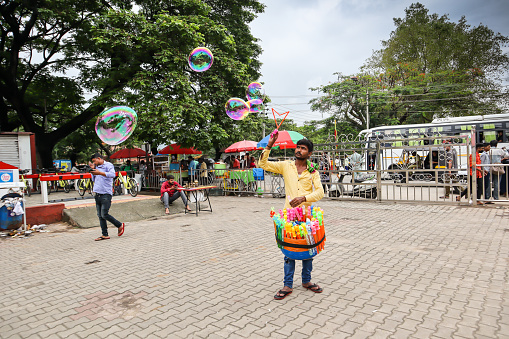A poor Toy seller seen creating soap bubbles with a bubble maker to attract children at the Royal palace in Mysore, India.