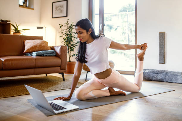 Young woman training yoga at home stock photo