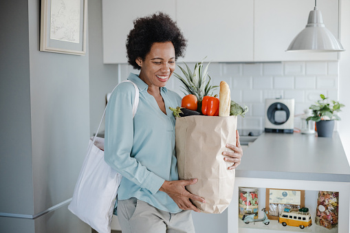 Woman holds bag full of groceries at home