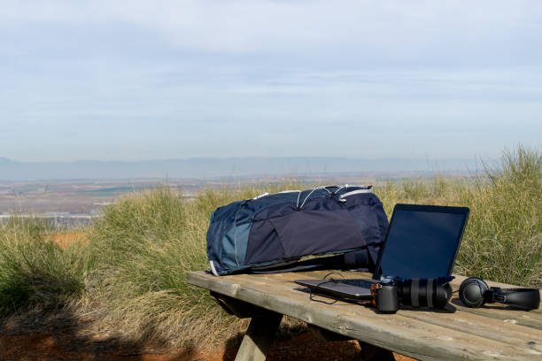 istock Backpack, computer, camera and headphones on a table in the nature 1399726069
