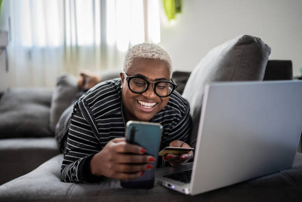 femmes d’âge mûr qui achètent en ligne à l’aide d’un téléphone portable à la maison - livraison à domicile photos et images de collection