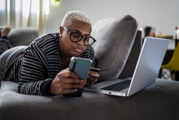 istock Mature women shopping online using mobile phone at home 1399727384