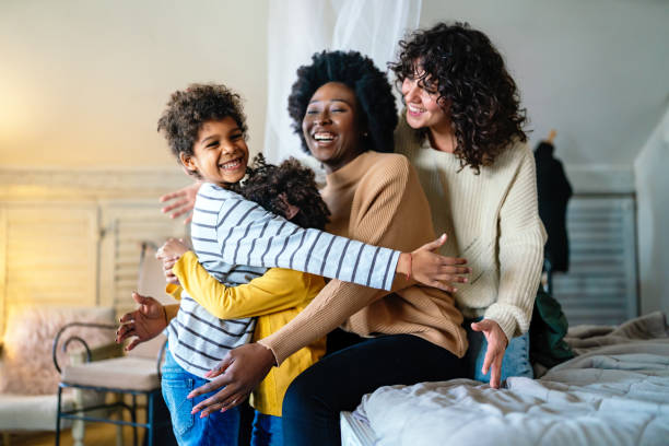 Happy lesbian multiethnic couple in love with childen at home. Family lgbt child happiness concept stock photo