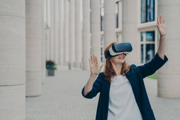istock Young ginger woman dressed formally stands outdoors and using VR headset 1399733377