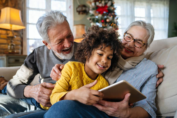 porträt der glücklichen großeltern mit kleinem mädchen mit digitalem tablet zu hause - grandparent grandfather granddaughter little girls stock-fotos und bilder